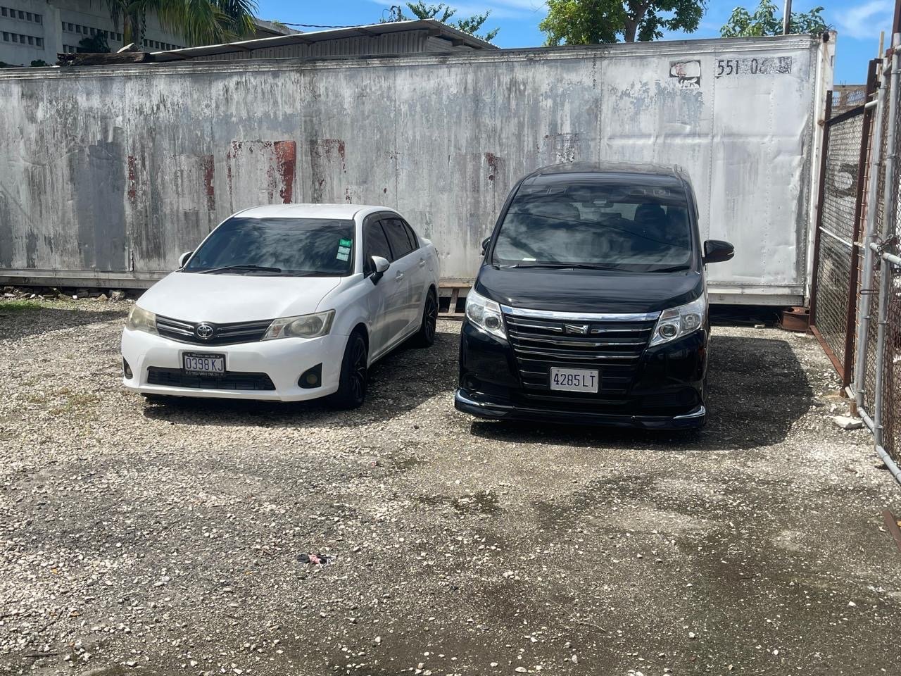 Front view of white Toyota sedan and black Toyota minivan in Jamaica